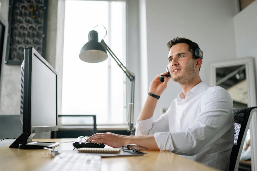 IT-Helpdesk-Spezialist, der in einem modernen Büro mit natürlichem Licht arbeitet und Kundensupport über ein Headset bietet.