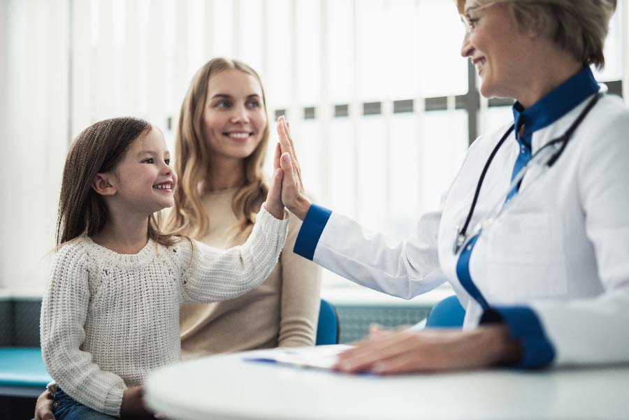 Kinderarzt interagiert mit Kind und Elternteil, symbolisiert den Aufbau einer Kinderarztpraxis.