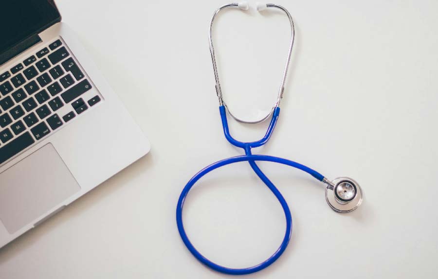 Stethoskop und Laptop auf weißem Hintergrund, symbolisiert die Modernisierung Ihrer Hausarztpraxis.